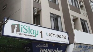 A multi-story building with balconies and a sign for 'iStay 1 Studio Apartment' with a contact number. - Istay Hotel Apartment 1 (Hanoi)