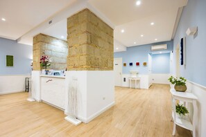 A modern hotel lobby with a reception desk, a brick accent wall, and a light blue wall. - Residenza Matilde by NapoliApartments (Naples)