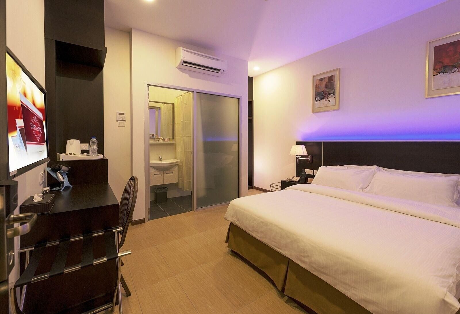 Ein Hotelzimmer mit Bett, Schreibtisch, Stuhl und einem Badezimmer mit Dusche.