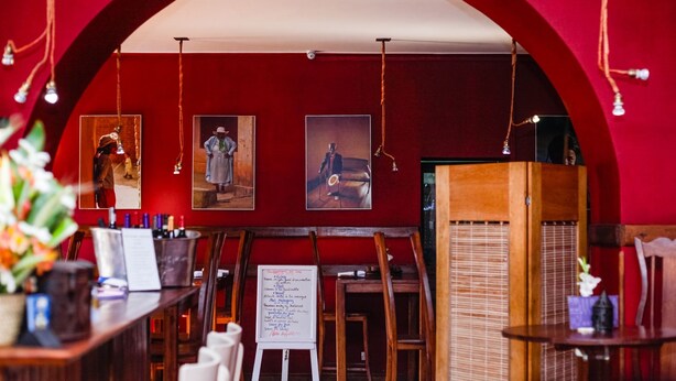 A restaurant interior with red walls, wooden furniture, and hanging lights. - Guest House Les 3 Metis (Antananarivo)