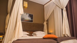 A bedroom with a bed, a nightstand, a lamp, and a painting on the wall. - Guest House Les 3 Metis (Antananarivo)