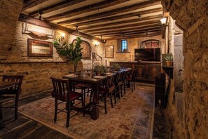 A rustic dining area with stone walls, wooden beams, and a long table with chairs. - THE George INN (Bath)