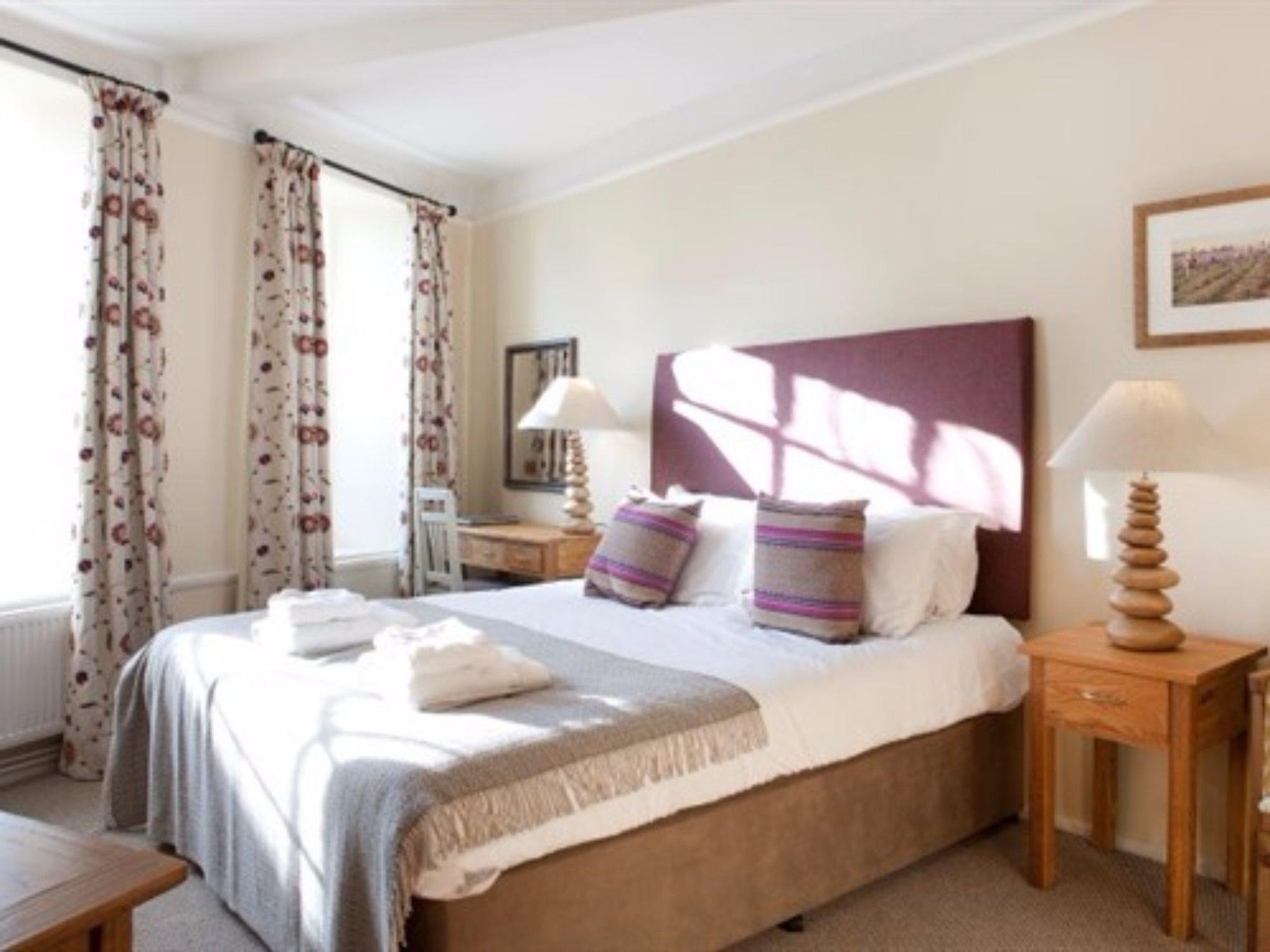 A neatly arranged hotel room with a bed, bedside tables, and a window with curtains.