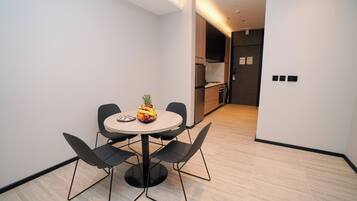 A modern dining area with a round table, four chairs, and a fruit bowl.