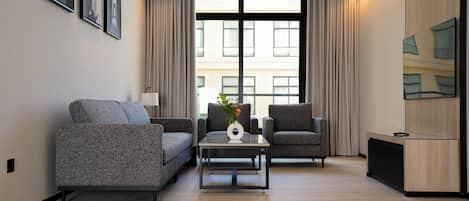 A modern living room with a sofa, two armchairs, a coffee table, and a TV on a wooden cabinet.