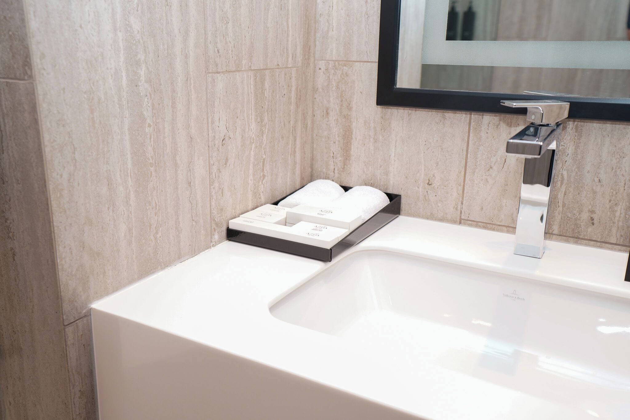 Un bagno moderno con un lavandino bianco, uno specchio e un portasapone.
