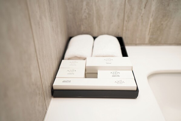 Une salle de bain avec un lavabo blanc, une serviette et une trousse de toilette.