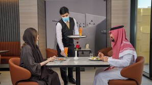 Uma área de refeições moderna com um garçom servindo uma bebida a uma mesa.