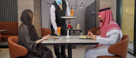 A modern dining area with a waiter serving a drink to a table.