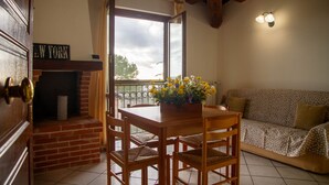 Una habitación acogedora con una mesa y sillas de madera, un sofá, una chimenea y vistas al cielo a través de una ventana.