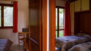 Un dormitorio con dos camas, un armario de madera, un escritorio con silla y una ventana con cortinas.