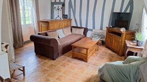 Uma sala de estar com um sofá marrom, uma mesa de centro de madeira, um rack para TV e um armário.
