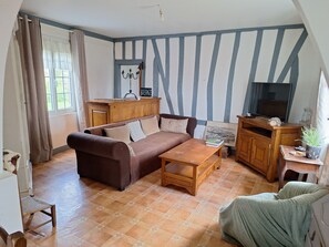 A living room with a brown sofa, a wooden coffee table, a TV stand, and a cabinet. - L'échappée Belle (Fresne-Cauverville)