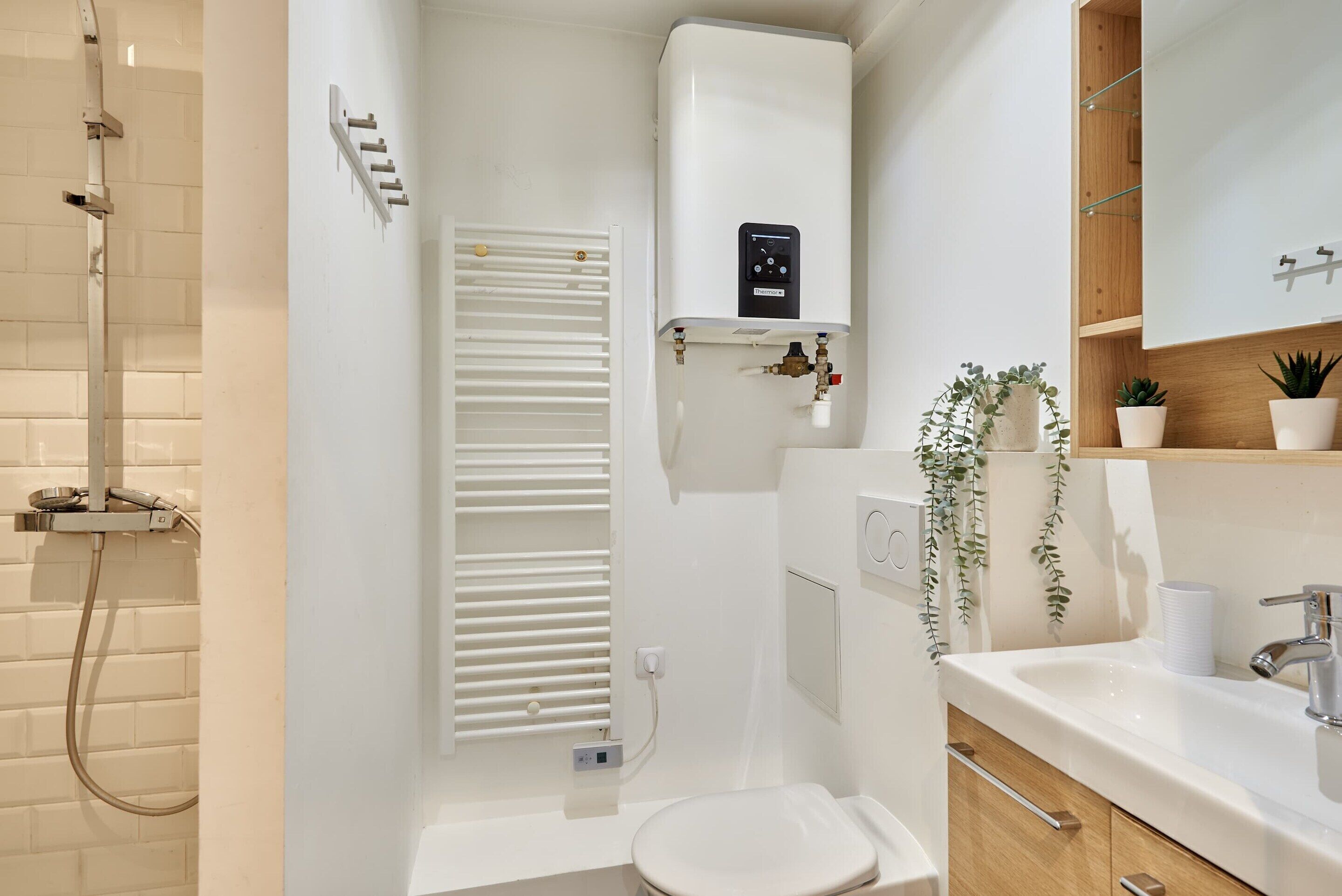 A modern bathroom with a shower, toilet, sink, and a built-in water heater.
