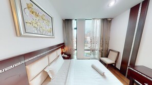 Une chambre d’hôtel avec un lit, une table de chevet, une chaise, une grande fenêtre avec des rideaux et un tableau encadré au mur.