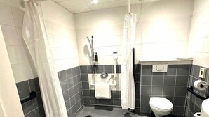 Een moderne badkamer met douche, toilet en wastafel.