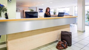 Een receptiebalie met een modern ontwerp, een laptop en een potplant.
