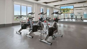Ett rymligt gym med flera motionscyklar, stora fönster och utsikt över omgivningarna.