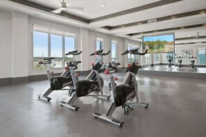 A spacious gym with multiple stationary bikes, large windows, and a view of the outdoors. - Modern Luxury 1BR Retreat in Clearwater (Clearwater)