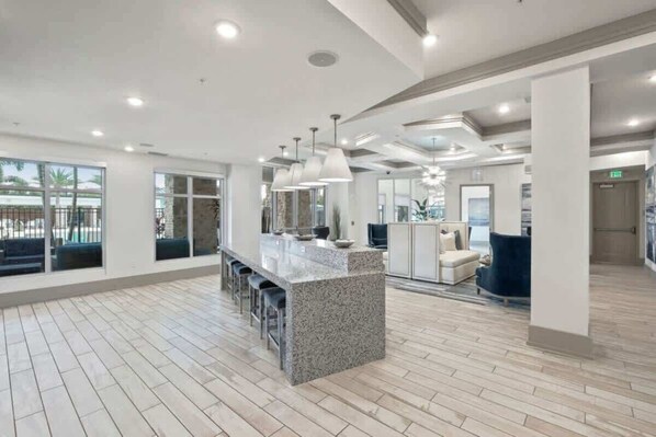 A spacious indoor area with a central granite island, bar stools, pendant lighting, and a view of the outdoors through large windows. - Modern Luxury 1BR Retreat in Clearwater (Clearwater)
