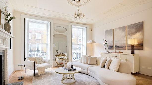 A spacious living room with a white sofa, a round coffee table, and a fireplace. There are large windows allowing natural light and a view of the city. - The West London House (London)