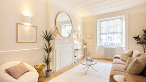 A well-lit living room with a fireplace, a round mirror, and a large window. - The West London House (London)