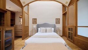 A spacious bedroom with a large bed, wooden furniture, and a view through an arched doorway. - The West London House (London)