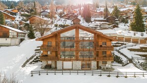 A multi-story wooden chalet with balconies, surrounded by snow-covered houses and trees. - Crevasse 07 - Elegant duplex & private sauna (Haute-Nendaz)