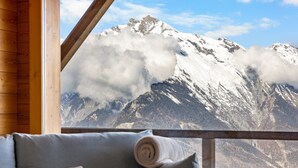 A mountain view from a wooden-framed window with a sofa and pillows. - Crevasse 07 - Elegant duplex & private sauna (Haute-Nendaz)