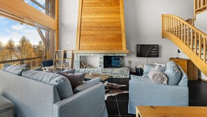 A spacious living area with a high wooden ceiling, a stone fireplace, and a cozy seating arrangement. - Crevasse 07 - Elegant duplex & private sauna (Haute-Nendaz)