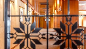 A hotel corridor with wooden walls, framed pictures, and a patterned metal gate. - Hotel La Plagne Le Terra Nova - Winter (La Plagne-Tarentaise)
