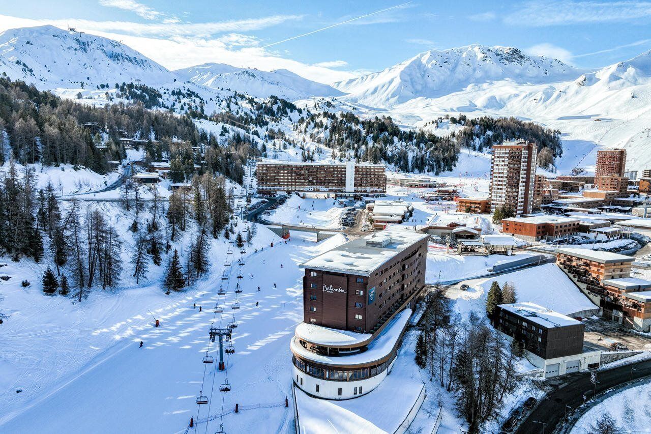Een hotel met een skilift, omgeven door besneeuwde bergen.