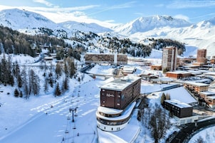 A hotel with a ski lift, surrounded by snow-covered mountains.