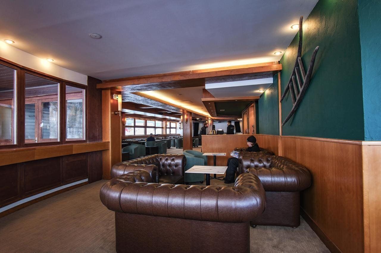 A restaurant with leather booths, wooden paneling, and a green accent wall.