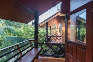 A wooden deck with a railing overlooking a lush garden. - Khaosok Rainforest Resort (Phanom)