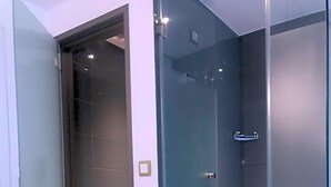 Ein modernes Badezimmer mit Duschkabine aus Glas, gefliestem Boden mit Muster und sichtbarer Toilette.