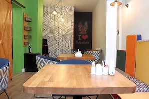 Un coin repas avec une table en bois, des chaises à motifs et un mur orné d’une œuvre d’art sur le thème des échecs.
