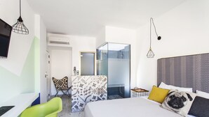 Ein modernes Hotelzimmer mit Bett, Schreibtisch, Stuhl und Duschbereich.