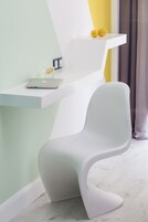 A modern room with a white chair, a white desk, and a white shelf with two yellow objects.