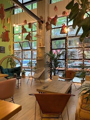 L’intérieur chaleureux d’un café, avec une table en bois, une chaise en osier et une vue sur la rue grâce à de grandes fenêtres.
