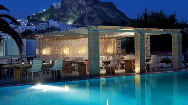 Un espace aménagé au bord de la piscine, avec des sièges extérieurs et une vue sur la montagne.