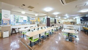 A cafeteria with multiple tables and chairs, a clock on the wall, and a window with a view of buildings outside. - Hotel 1 2 3 Kurashiki (Kurashiki)