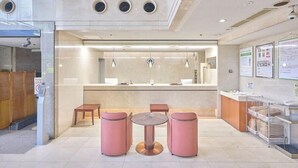 A modern reception area with a counter, seating, and informational posters. - Hotel 1 2 3 Kurashiki (Kurashiki)