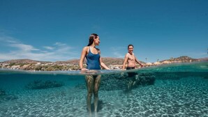 Two people standing on a beach with clear water and a view of the landscape in the background. - Iris Apartments and Rooms (Kantanos-Selino)