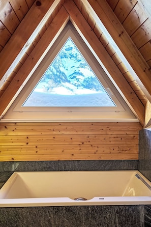 A bathroom with a skylight, wooden ceiling, and a bathtub. - Edelweiss B by Interhome (Leukerbad)
