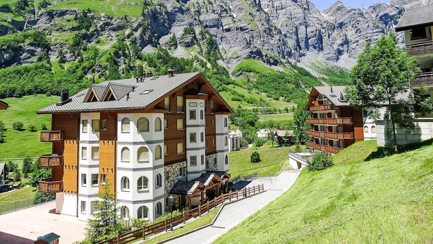 Et fjeldhotel med flere bygninger, en belagt sti og udsigt til barske bjerge.