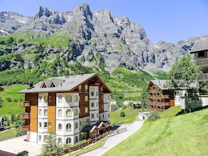 A mountain lodge with multiple buildings, a paved pathway, and a view of rugged mountains. - Edelweiss B by Interhome (Leukerbad)