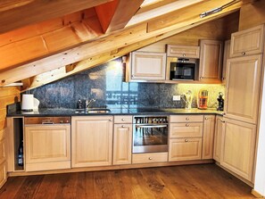 A kitchen with wooden cabinets, a microwave, and a stove. - Edelweiss B by Interhome (Leukerbad)