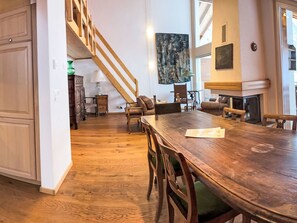 A spacious dining area with a wooden table and chairs, a staircase leading to an upper level, and a fireplace. - Edelweiss B by Interhome (Leukerbad)