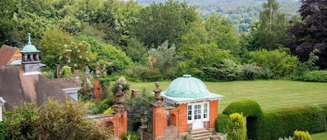 A garden with a gazebo, a brick structure, and a well-maintained lawn.
